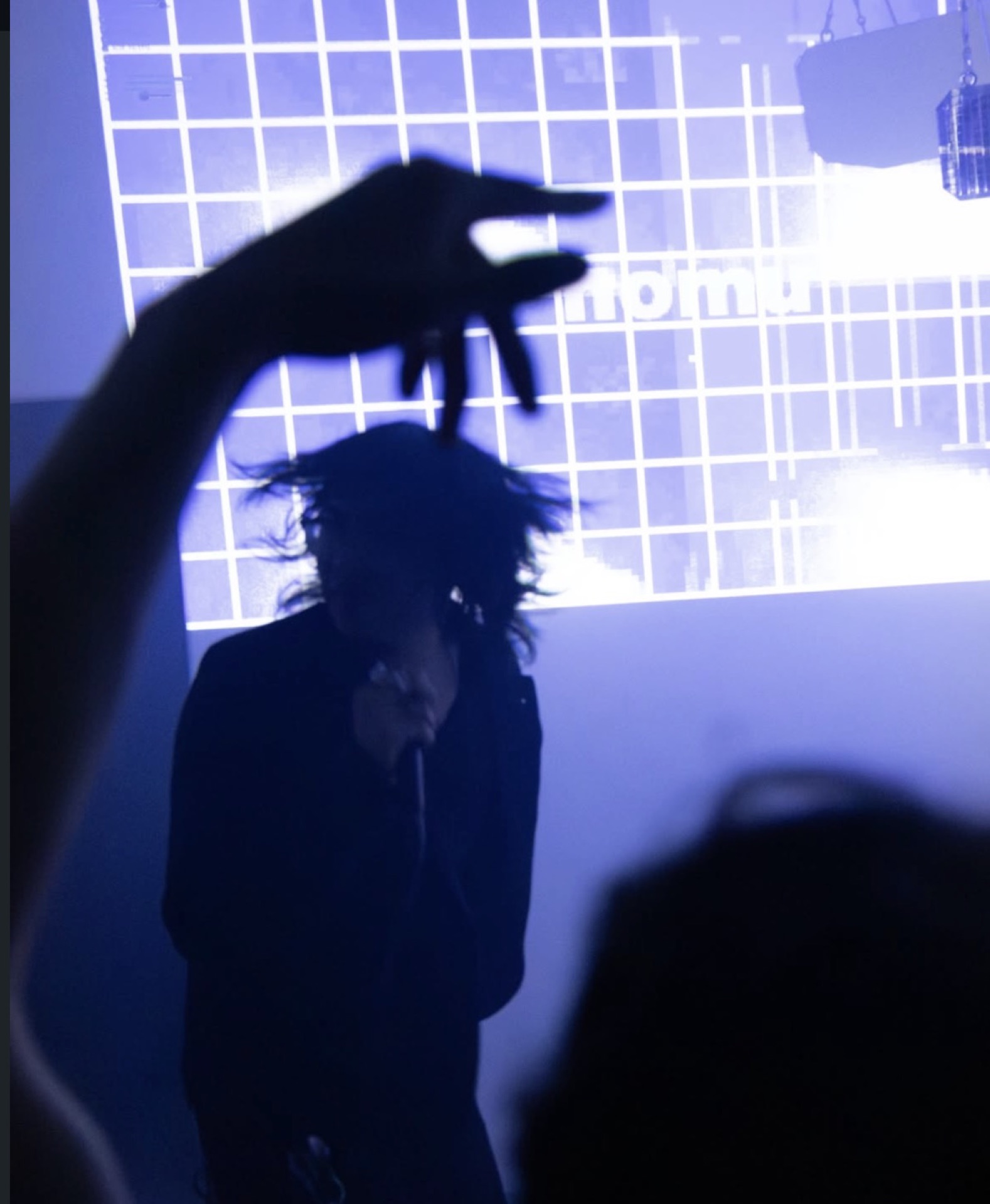 nomu live in blue light, realtime grid visuals reading nomu behind him