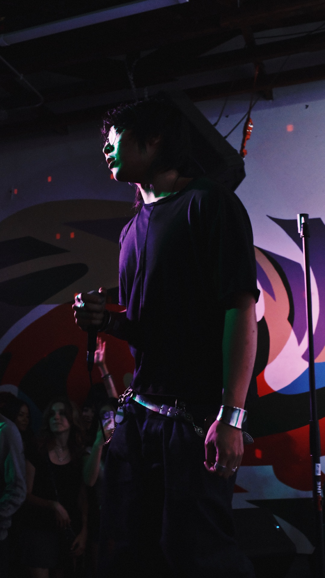 nomu on stage in profile in front of a mural wall